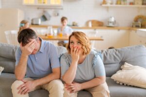 Tense Parents Sitting On Sofa Tired Crazy Loud Hyperactive Little Kids