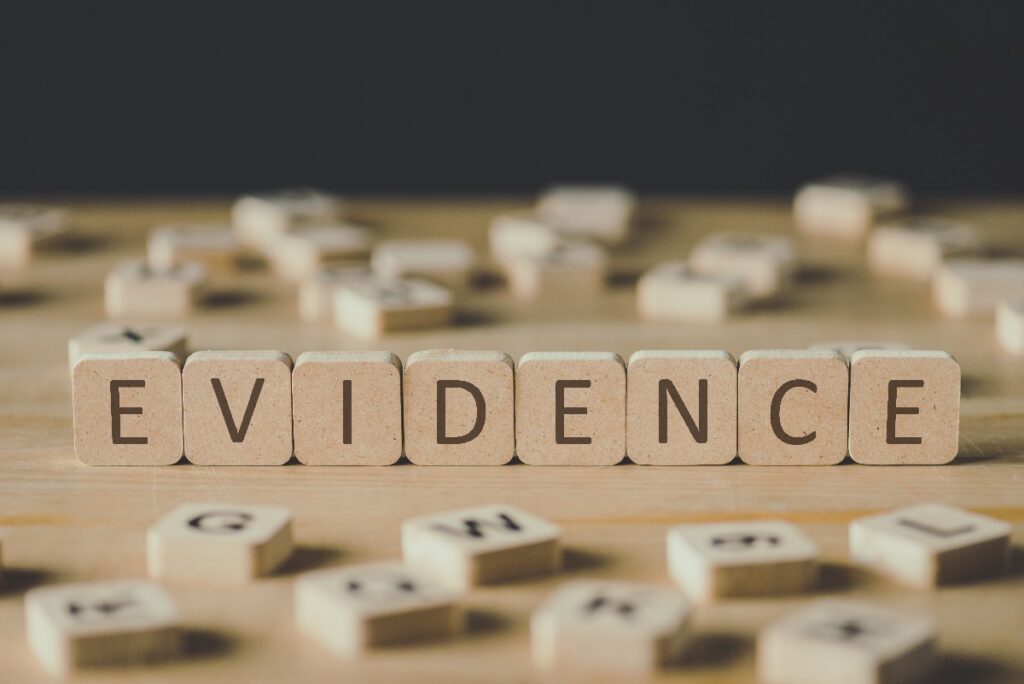 Selective Focus Of Word Evidence Made Of Cubes Surrounded By Blocks With Letters On Wooden Surface