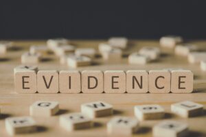 Selective Focus Of Word Evidence Made Of Cubes Surrounded By Blocks With Letters On Wooden Surface